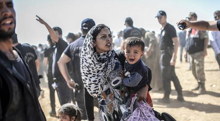 امرأة سورية رفقة طفليها تعبر الحدود من سوريا إلى تركيا