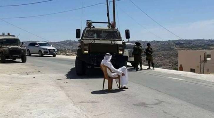 مسن فلسطيني يجلس أمام الآلية العسكرية 