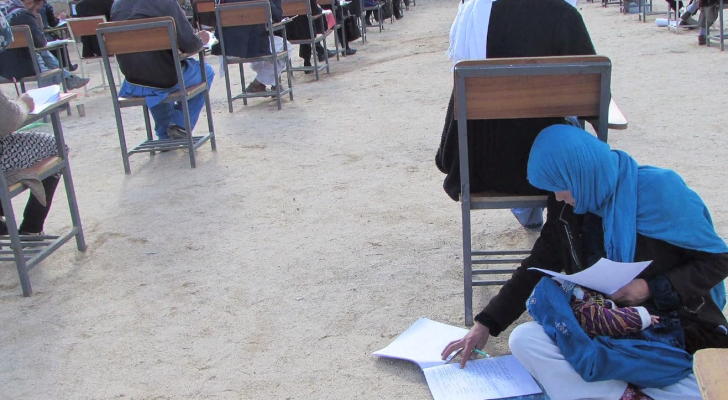 افغانية تفترش الأرض وتعتني بطفلها أثناء الدراسة