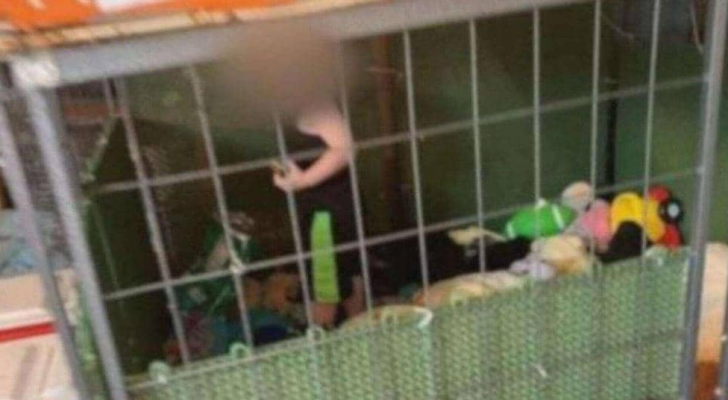 طفل صغير لا يتجاوز عمره 18 شهرا داخل قفص للكلاب