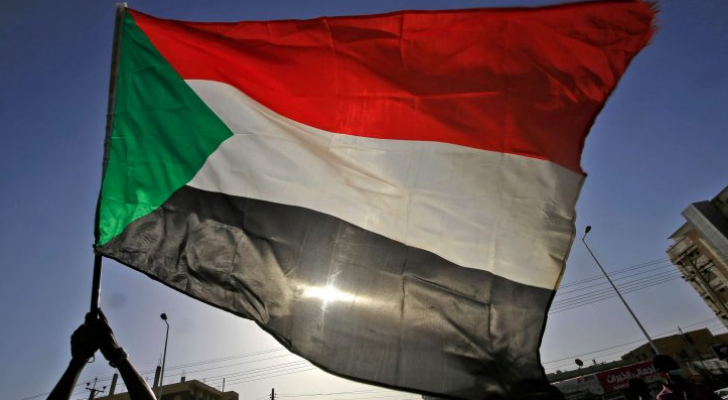 سوداني يرفع علم بلاده بإحدى المظاهرات