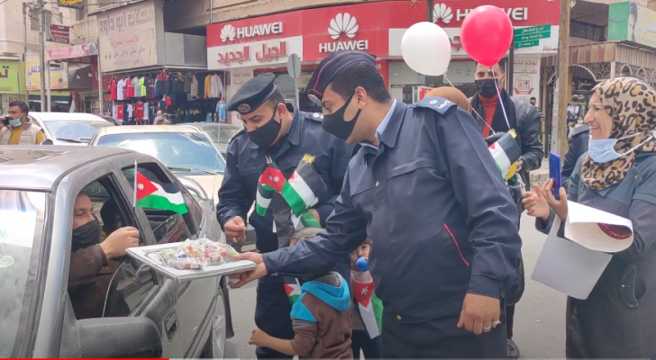 شرطيان يوزعان الأعلام والحلوى على مواطني المفرق