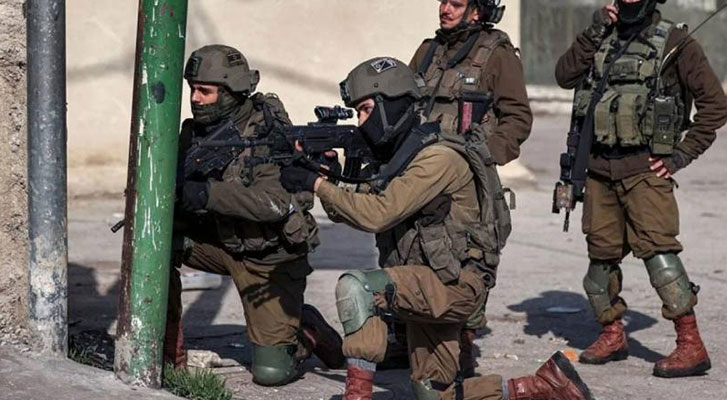 جندي إسرائيلي متأهب لتوجيه رصاص بندقيته نحو فلسطينيين