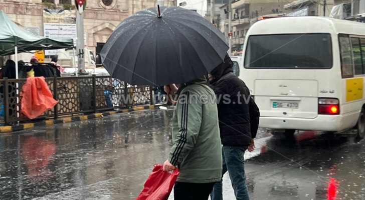 شخص يحمل مظلة في أحد شواع العاصمة عمان