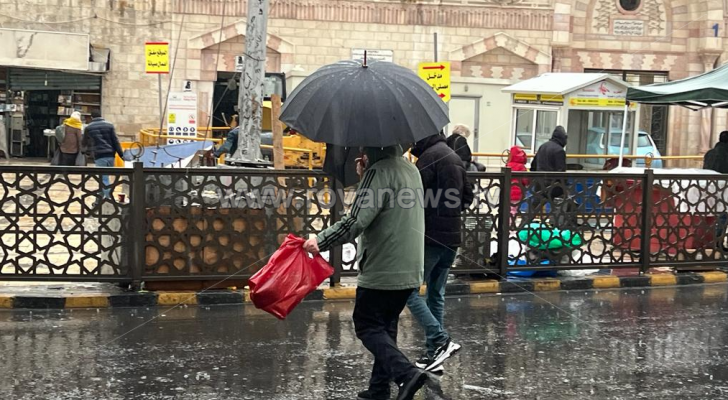 أشخاص يحملون مظلة في العاصمة عمان