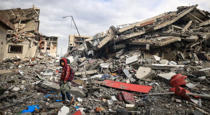 فلسطيني فوق أنقاض منزله المدمر في غزة حاملا حقيبة والدته
