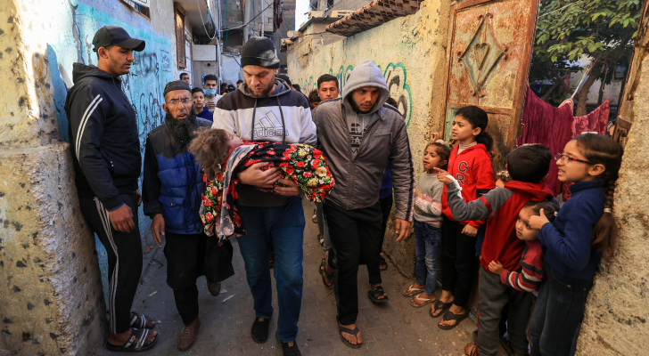فلسطيني يحمل طفلة استشهدت بعدوان الاحتلال بغزة