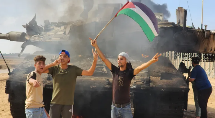 فلسطينيون يحتفلون فوق دبابة أحرقها المقاومون في قطاع غزة