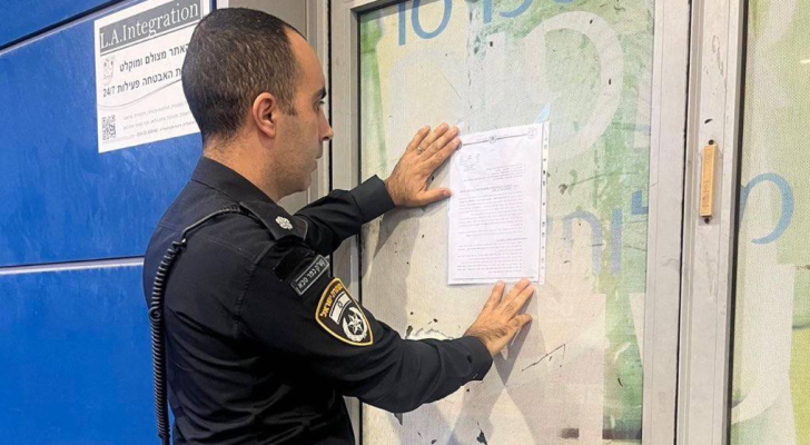 أحد عناصر شرطة الاحتلال لحظة إغلاق محطة غسيل المركبات في رعنانا