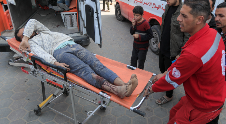 مسعف يحمل ينقل أحد الأشخاص الجرحى بعدوان الاحتلال على غزة