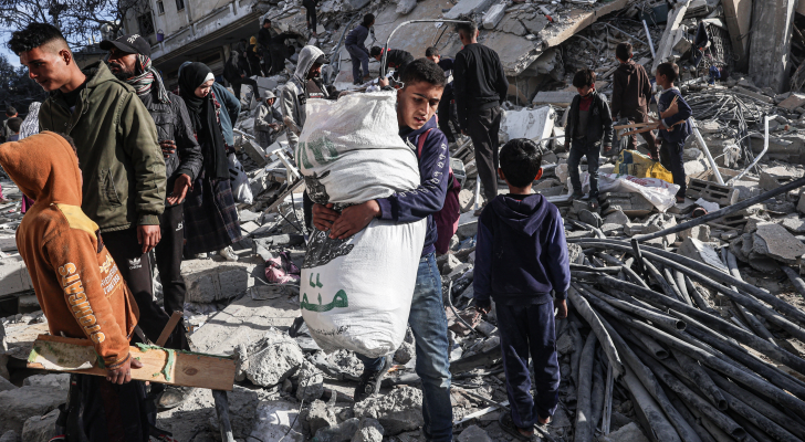فلسطينيون يسيرون بين أنقاض مبنى سكني أصيب في غارة جوية للاحتلال في رفح جنوبي قطاع غزة