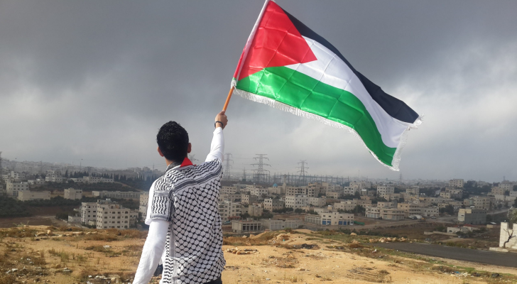فلسطيني يرفع علم بلاده