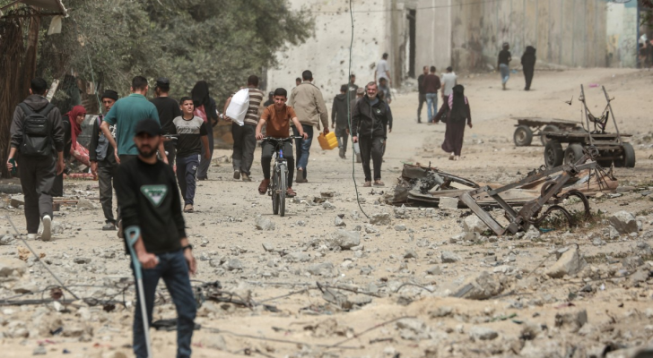 فلسطينيون يسيرون وسط الأنقاض في مدينة النصيرات في وسط قطاع غزة