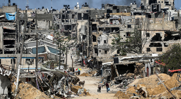 فلسطينيون يمرون بين المباني المدمرة في خان يونس بقطاع غزة
