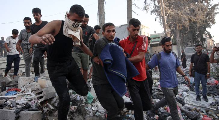 فلسطينيون يحملون جثمان شهيد بعد غارة للاحتلال استهدفت مدرسة في حي الزيتون