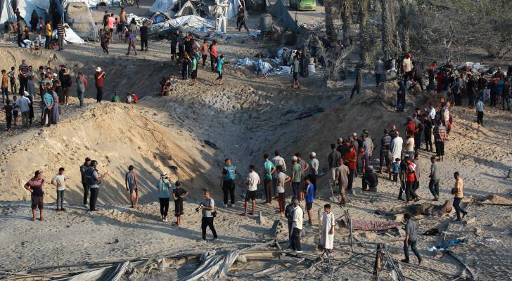 فلسطينيون يتفقدون الأضرار في موقع ضربات الاحتلال على مخيم مؤقت للنازحين في مواصي خان يونس