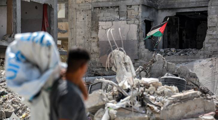 فلسطيني ينظر إلى علم بلاده المعلق بين الركام