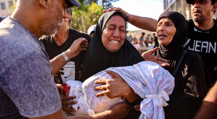 فلسطينية تحمل رضيعها الشهيد في غزة