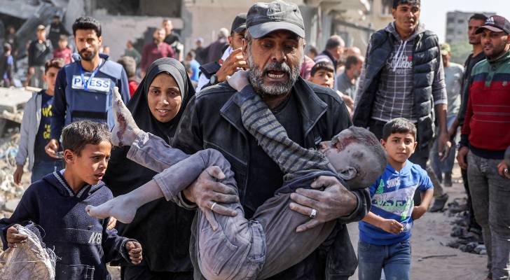 فلسطيني يحمل ابنه لمحاولة إنقاذه في قطاع غزة "أ ف ب"