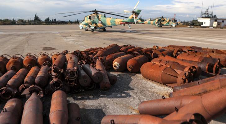 ذخائر برميلية متفجرة ملقاة على مدرج بالقرب من مروحيات روسية من طراز Mi-24 تابعة لسلاح الجو السوري