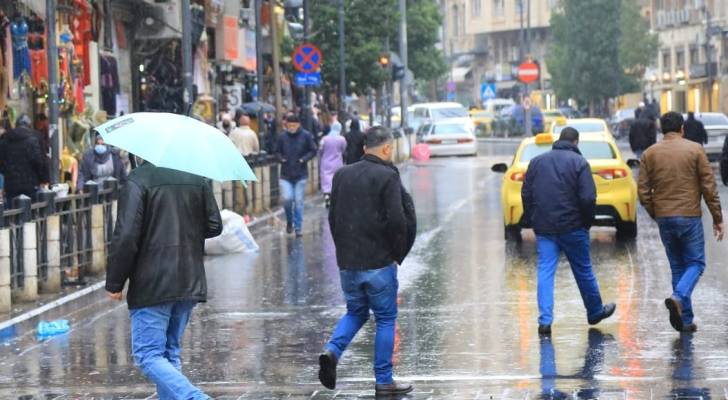 أشخاص يسيرون وسط انهمار المطر