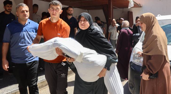 فلسطينية تحمل جثمان ابنها الشهيد في غزة