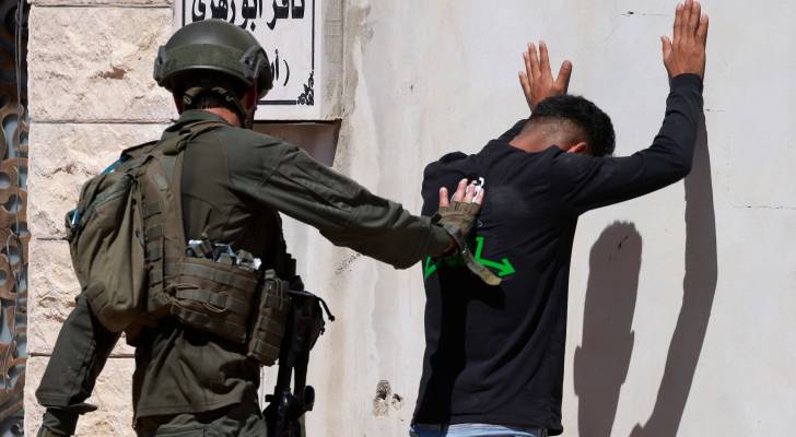 جندي من جيش الاحتلال يفتش شابا فلسطينيا في الضفة الغربية
