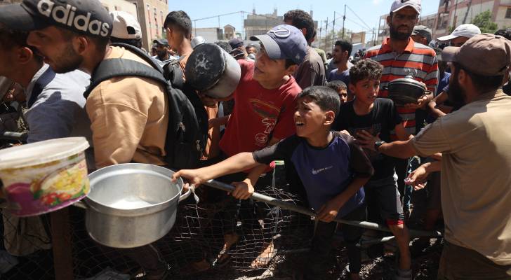 يتجمع فلسطينيون عند نقطة توزيع غذاء في مخيم النصيرات للاجئين وسط قطاع غزة،