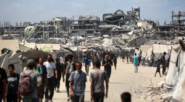 فلسطينيون يسيرون قرب مبان مدمرة بغزة