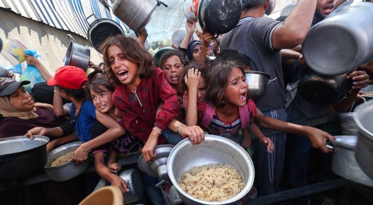 فلسطينيون في نقطة توزيع مساعدات غذائية في مخيم النصيرات في قطاع غزة