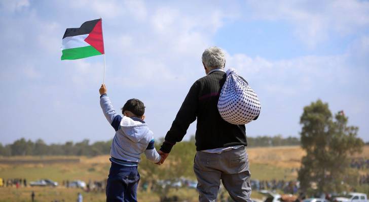 فلسطيني يمسك بيد ابنه الذي يحمل علم علم فلسطين