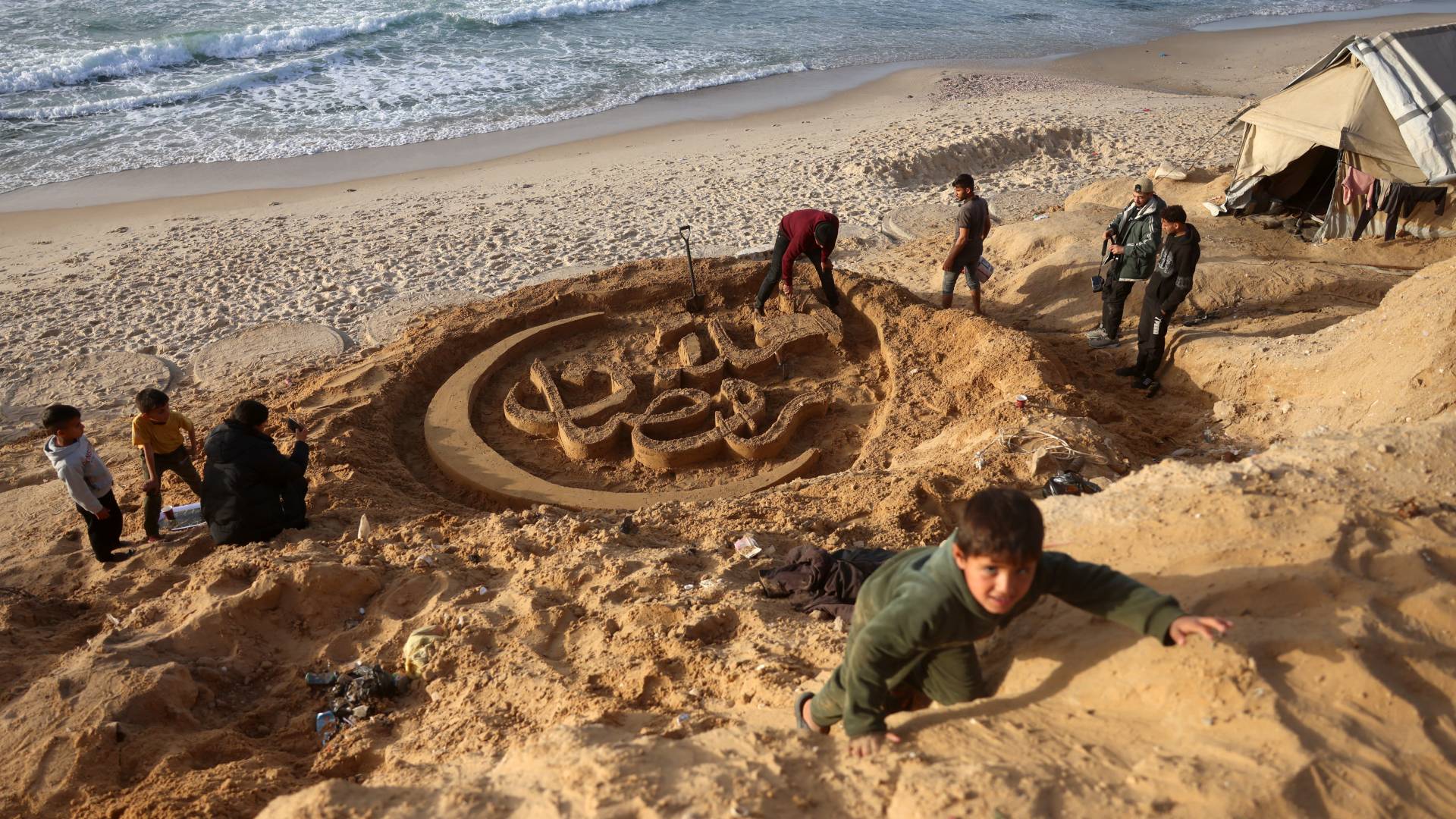 بأنامل فنان نازح.. عبارة "أهلا رمضان" تنقش على رمال خان يونس في رسالة صمود -فيديو