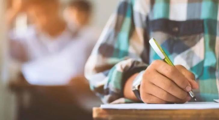 طالب يمسك قلم لحل ورقة الاختبار