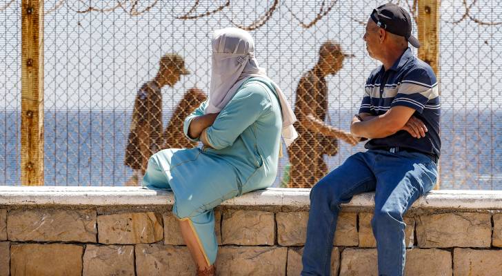 شخصين ينظران إلى المهاجرين إلى إسبانيا وهم عائدون للمغرب