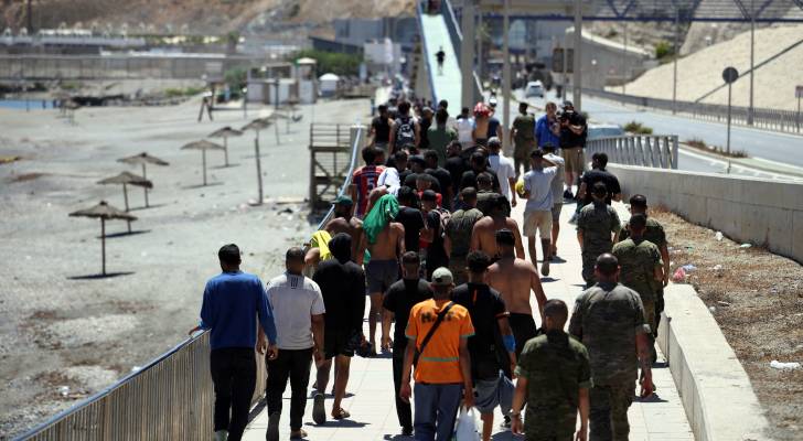 يعبر المهاجرون بوابة الحدود بين سبتة والمغرب في جيب سبتة الإسباني