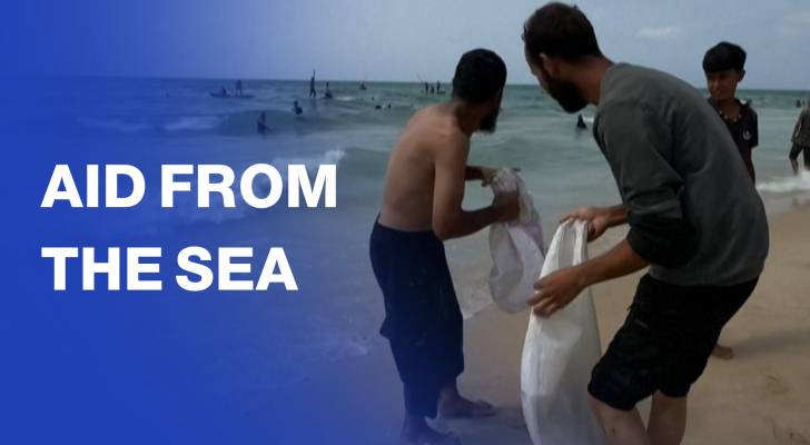 Palestinians go into the sea to collect aid airdropped over central Gaza