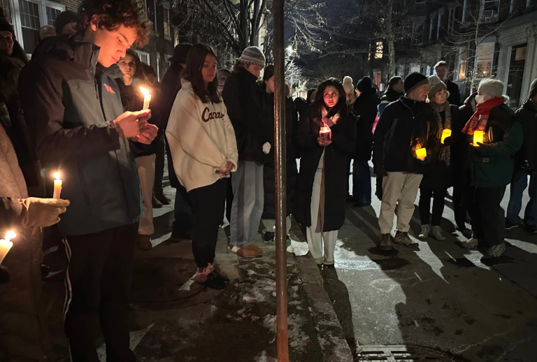 A crowd of people holding candles gather outside the home of Massachusetts Institute of Technology professor Nuno F.G. Loureiro in Brookline, Mass., Tuesday, Dec. 16, 2025.